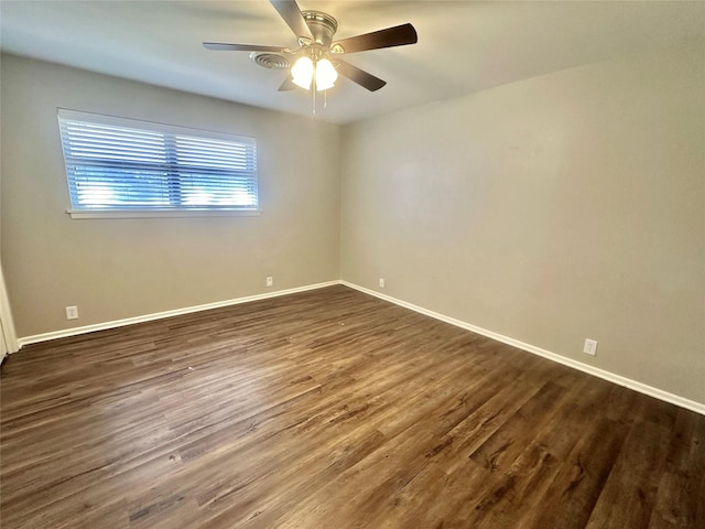 unfurnished room featuring dark wood-style flooring, ceiling fan, and baseboards