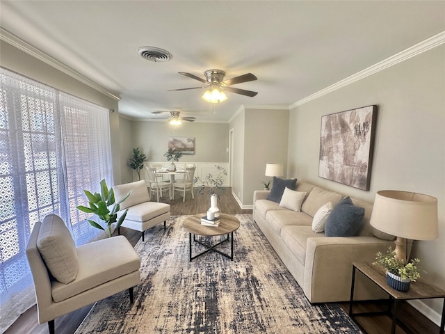 living area with a ceiling fan, visible vents, crown molding, and wood finished floors