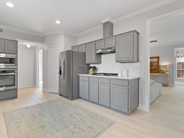 kitchen featuring a notable chandelier, gray cabinets, under cabinet range hood, backsplash, and stainless steel appliances