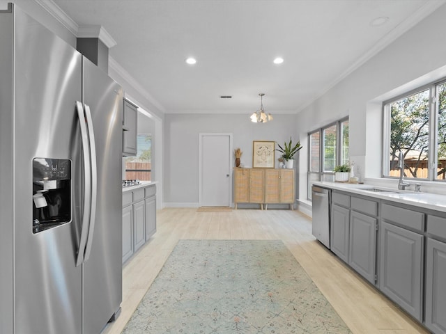 kitchen with light countertops, gray cabinets, appliances with stainless steel finishes, and ornamental molding