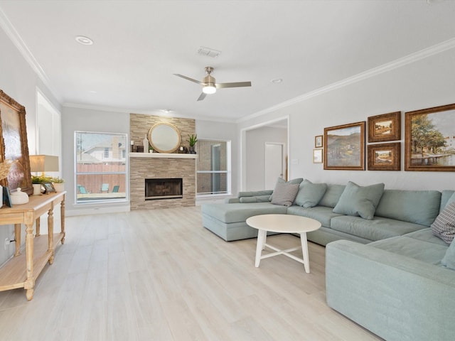 living area with visible vents, a fireplace, light wood-style floors, and ornamental molding