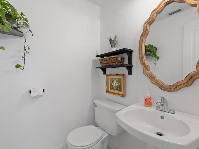 bathroom featuring toilet, baseboards, visible vents, and a sink