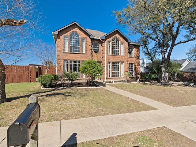 colonial house with brick siding, a front yard, and fence