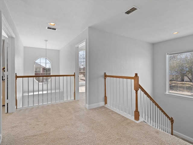 hallway featuring an upstairs landing, visible vents, carpet flooring, and baseboards