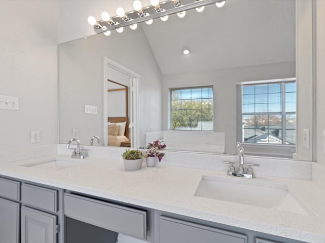 ensuite bathroom featuring ensuite bath, vaulted ceiling, plenty of natural light, and vanity