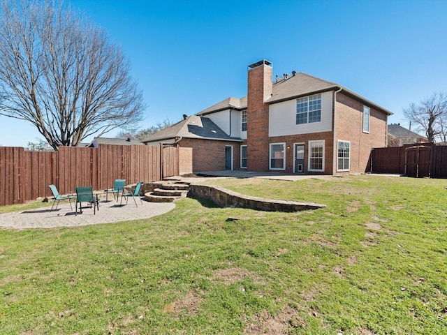 rear view of house featuring a yard, a fenced backyard, a chimney, and a patio