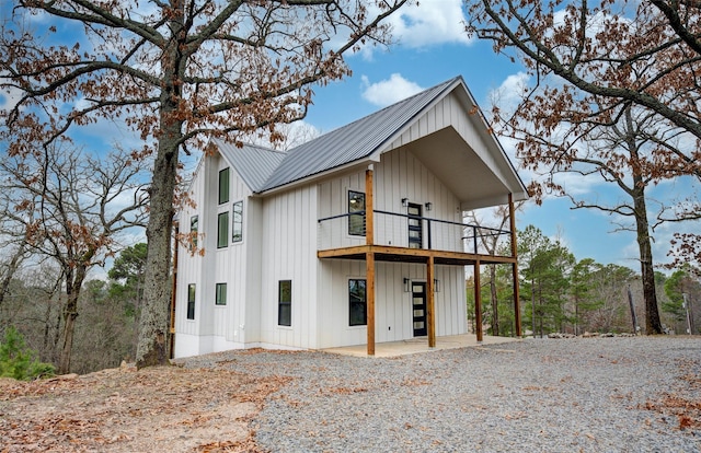 view of front facade featuring a balcony, metal roof, and board and batten siding