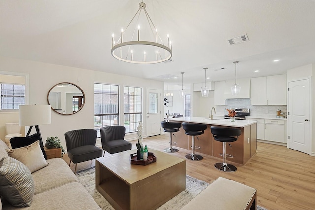 living area featuring light wood finished floors, visible vents, lofted ceiling, a chandelier, and recessed lighting