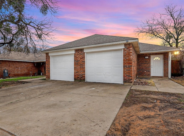 view of front of house with a garage, brick siding, driveway, and roof with shingles