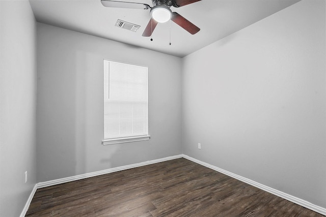 empty room featuring dark wood-style floors, a ceiling fan, visible vents, and baseboards