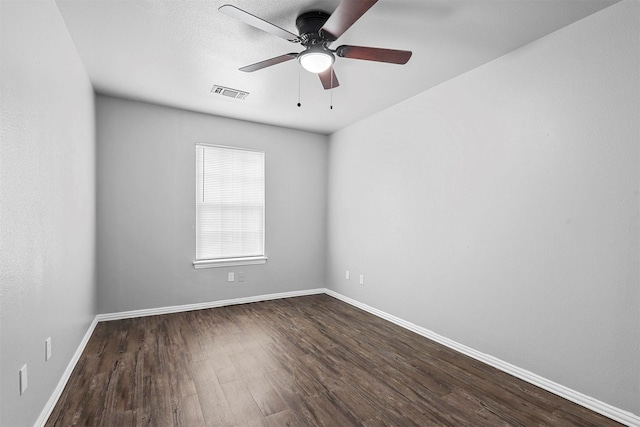 empty room featuring visible vents, dark wood finished floors, baseboards, and ceiling fan