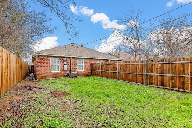 back of property with a yard, brick siding, central AC unit, and a fenced backyard