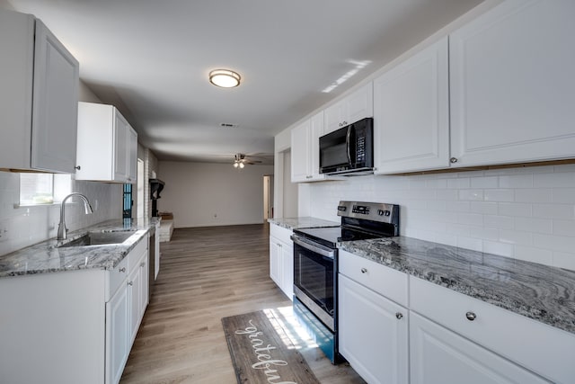 kitchen featuring black microwave, decorative backsplash, a sink, and electric range