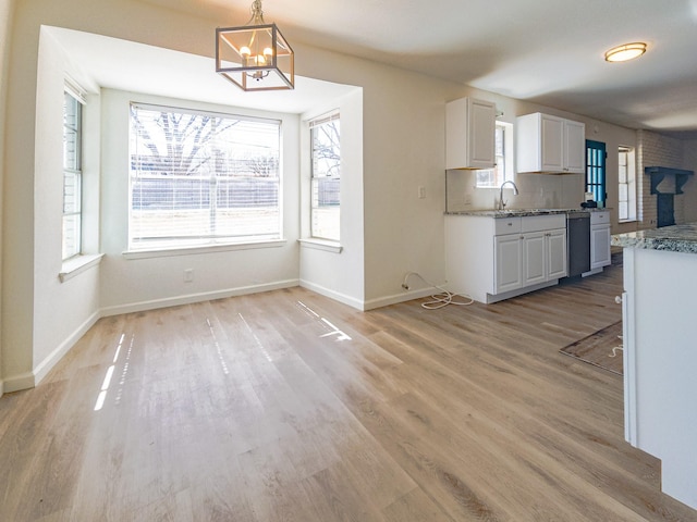 kitchen with decorative light fixtures, white cabinetry, a chandelier, light wood-style floors, and tasteful backsplash