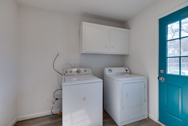 clothes washing area featuring cabinet space, independent washer and dryer, wood finished floors, and a healthy amount of sunlight