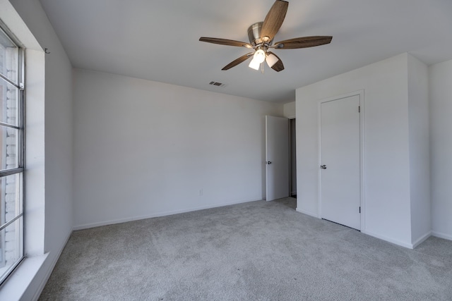 unfurnished bedroom with carpet flooring, a ceiling fan, visible vents, and multiple windows