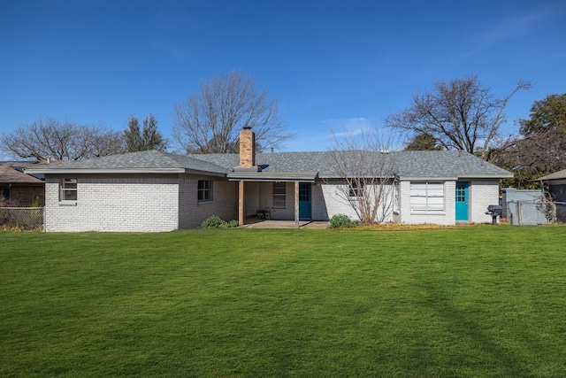 back of house with a yard, brick siding, and a chimney