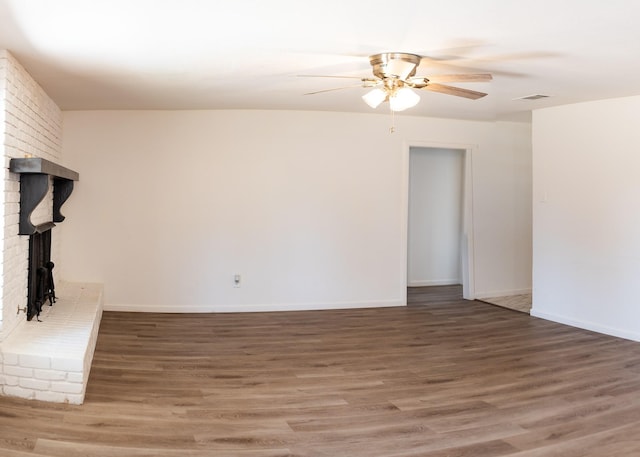 unfurnished living room featuring wood finished floors, visible vents, a fireplace, a ceiling fan, and baseboards