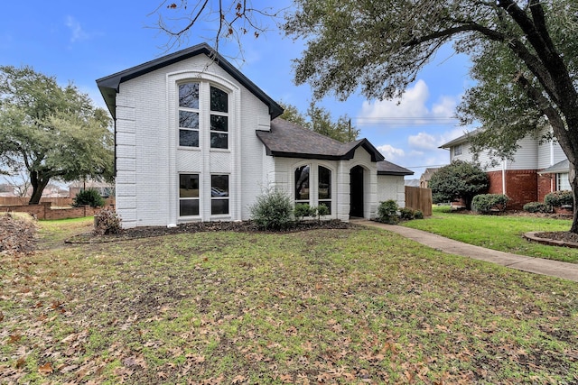 view of front of home featuring brick siding, a front yard, and fence