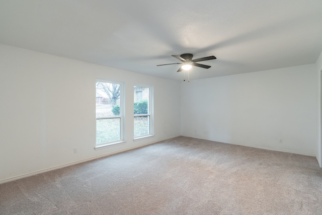 spare room with baseboards, a ceiling fan, and light colored carpet