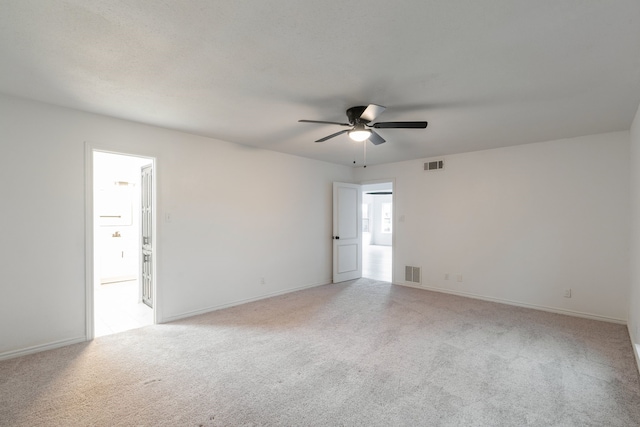 empty room with baseboards, visible vents, a ceiling fan, and light colored carpet