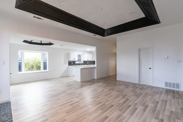 unfurnished living room featuring light wood-type flooring, visible vents, and baseboards