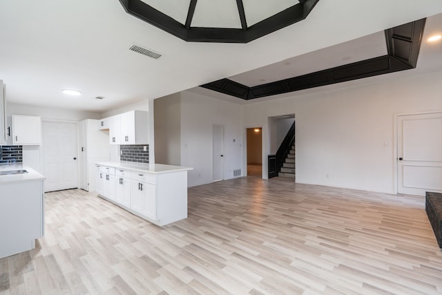 kitchen featuring light countertops, visible vents, backsplash, open floor plan, and white cabinetry