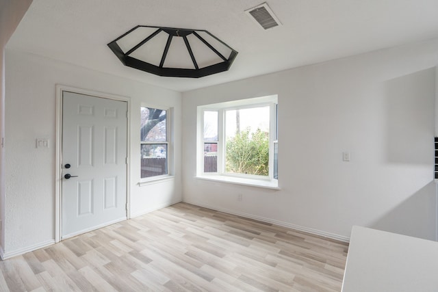 spare room with light wood-style flooring, visible vents, and baseboards