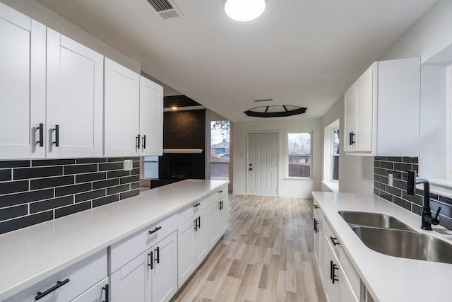 kitchen featuring visible vents, light countertops, a sink, and white cabinetry