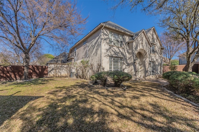 view of property exterior with a lawn, fence, and stucco siding