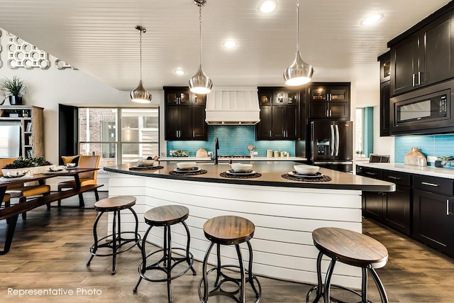 1231 Streamside Dr, Prosper, TX 75078 - kitchen featuring fridge with ice dispenser, black microwave, custom exhaust hood, a kitchen bar, and recessed lighting