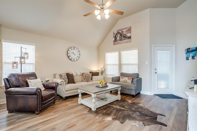 living area featuring light wood-style floors, baseboards, high vaulted ceiling, and a ceiling fan