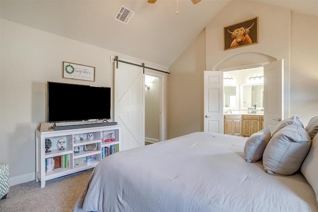 bedroom featuring lofted ceiling, carpet, a barn door, and visible vents