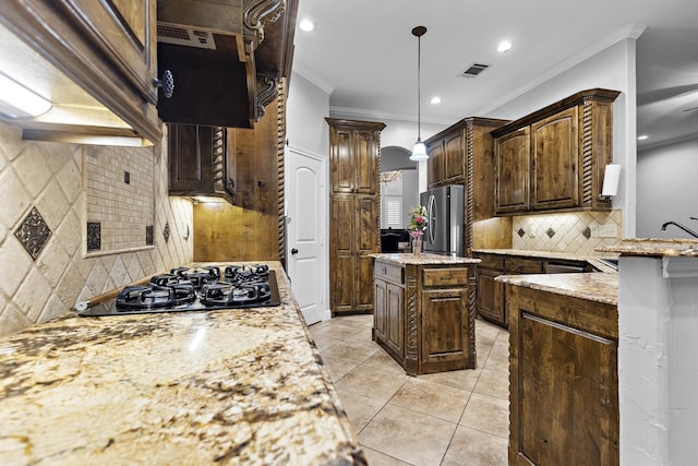 kitchen with visible vents, light stone counters, a center island, freestanding refrigerator, and gas cooktop