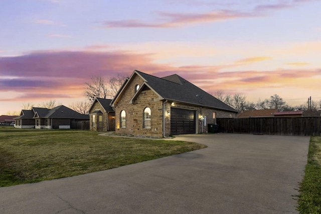 french provincial home with an attached garage, fence, driveway, and a front lawn