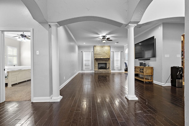 unfurnished living room with ornate columns, ceiling fan, ornamental molding, and dark wood-type flooring