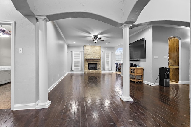 unfurnished living room featuring arched walkways, a ceiling fan, ornamental molding, wood finished floors, and ornate columns