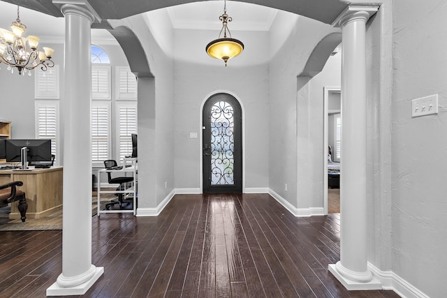 entrance foyer featuring dark wood-style floors, decorative columns, arched walkways, and ornamental molding