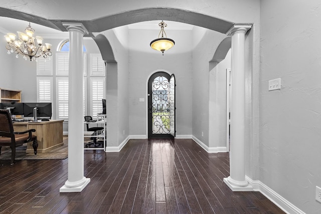 entrance foyer featuring decorative columns, arched walkways, and dark wood-type flooring