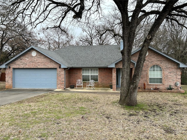 ranch-style home with brick siding, roof with shingles, concrete driveway, an attached garage, and a front lawn