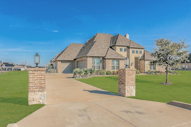 french country home featuring a garage, brick siding, driveway, roof with shingles, and a front lawn