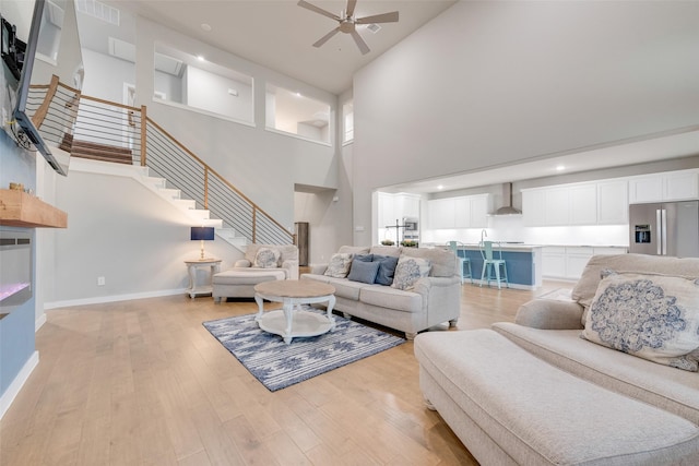 living area featuring light wood finished floors, ceiling fan, stairs, and visible vents