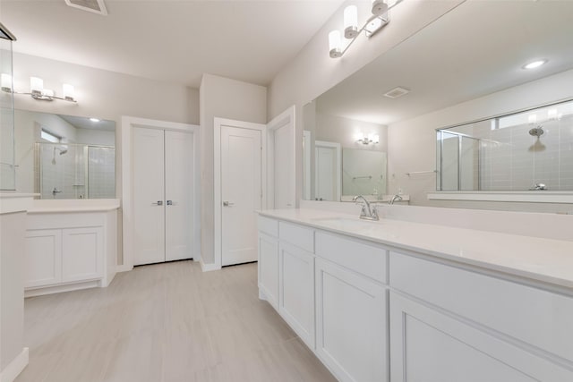 bathroom with a closet, two vanities, a sink, and a shower stall