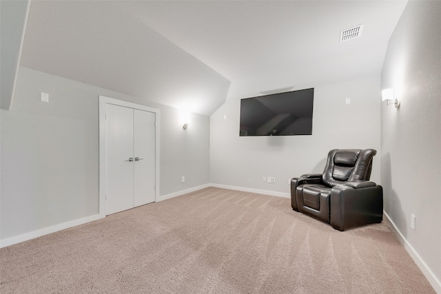 sitting room with vaulted ceiling, baseboards, visible vents, and light colored carpet