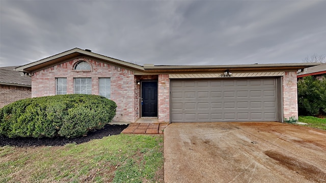 single story home with a garage, concrete driveway, and brick siding