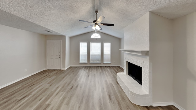 unfurnished living room with baseboards, visible vents, light wood-style floors, lofted ceiling, and a brick fireplace