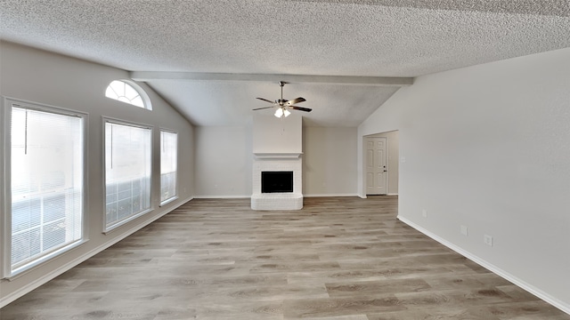 unfurnished living room with lofted ceiling with beams, a textured ceiling, a fireplace, and light wood-style floors