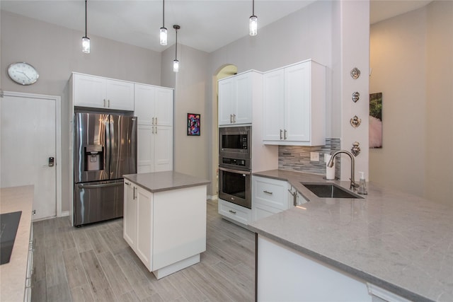 kitchen with stainless steel appliances, hanging light fixtures, backsplash, and white cabinetry