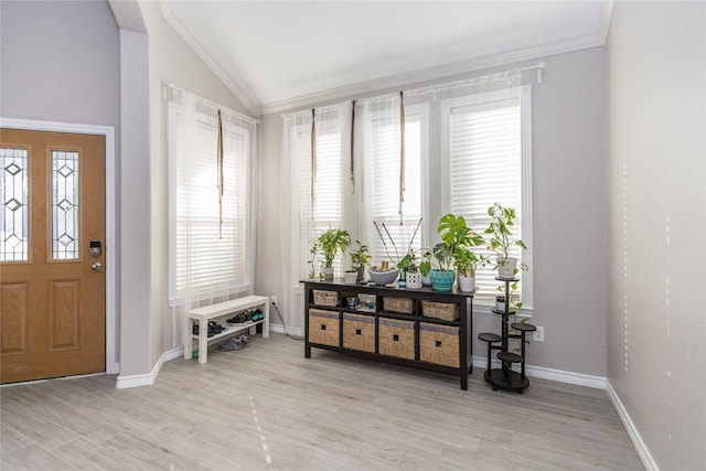 foyer featuring vaulted ceiling, light wood finished floors, crown molding, and baseboards