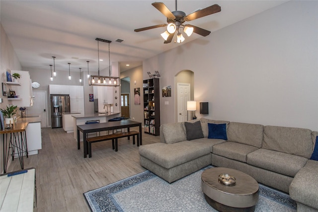 living room featuring arched walkways, ceiling fan, light wood-type flooring, and visible vents